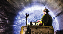 man in hardhat riding tramway through a tunnel